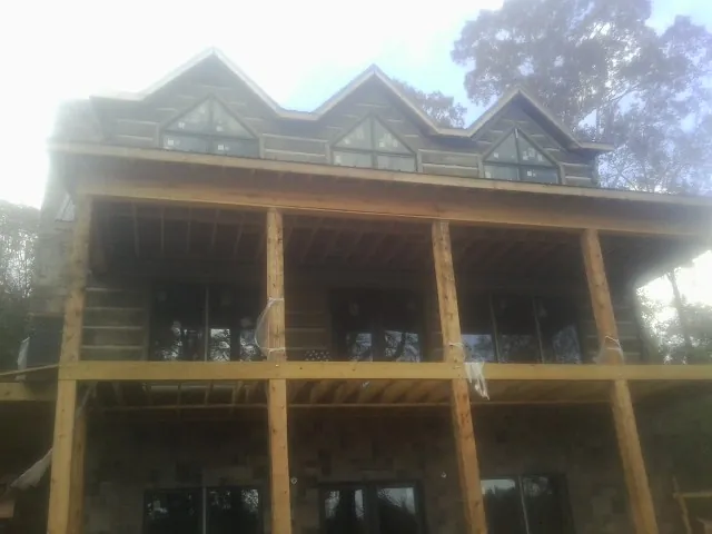 Dormers and porch framing on a large log home under construction — Roof Coating work by our crew in Hospers
