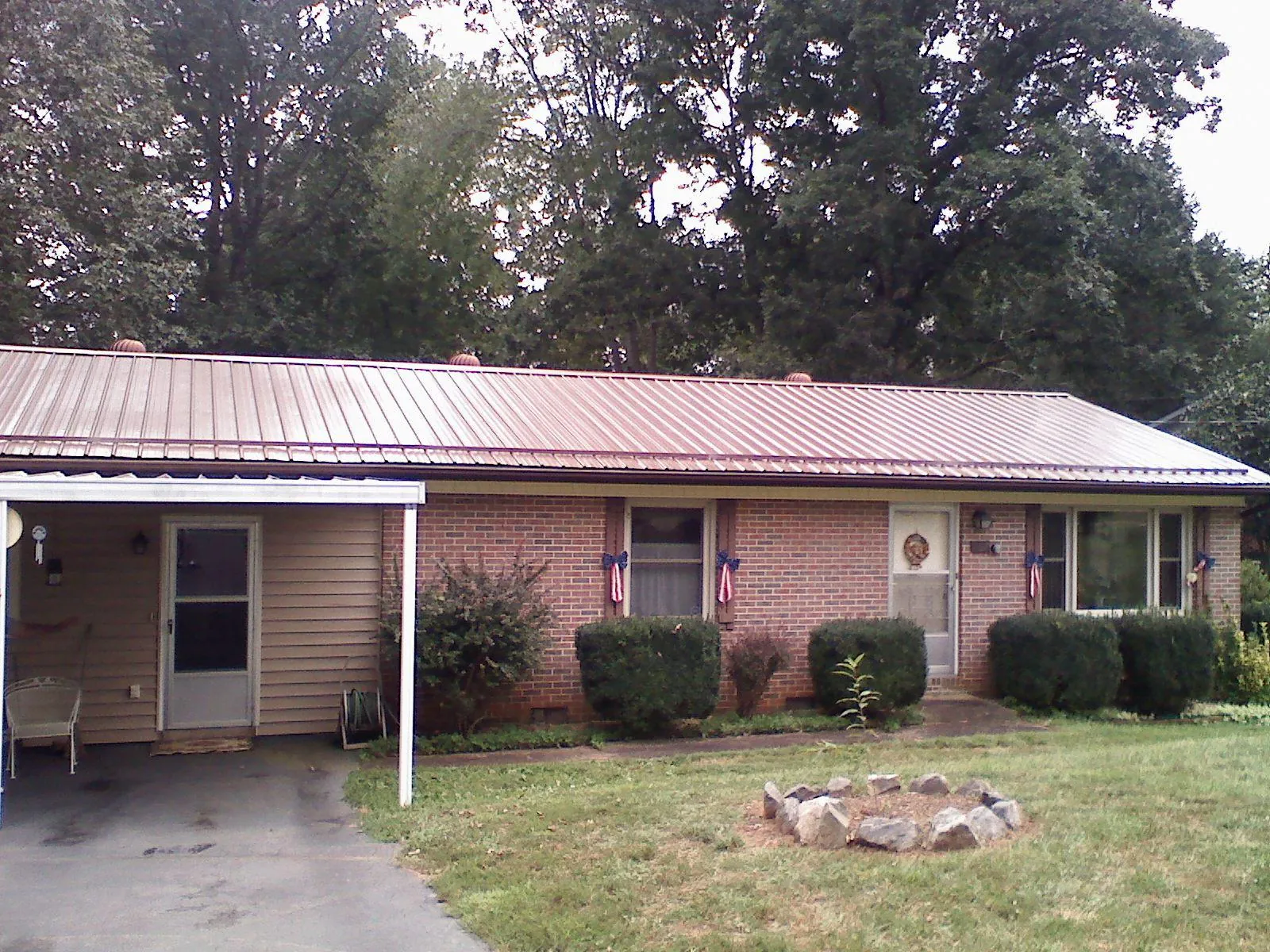 Bronze metal roof and carport on a brick ranch home — Roof Repair work by our crew in Hospers