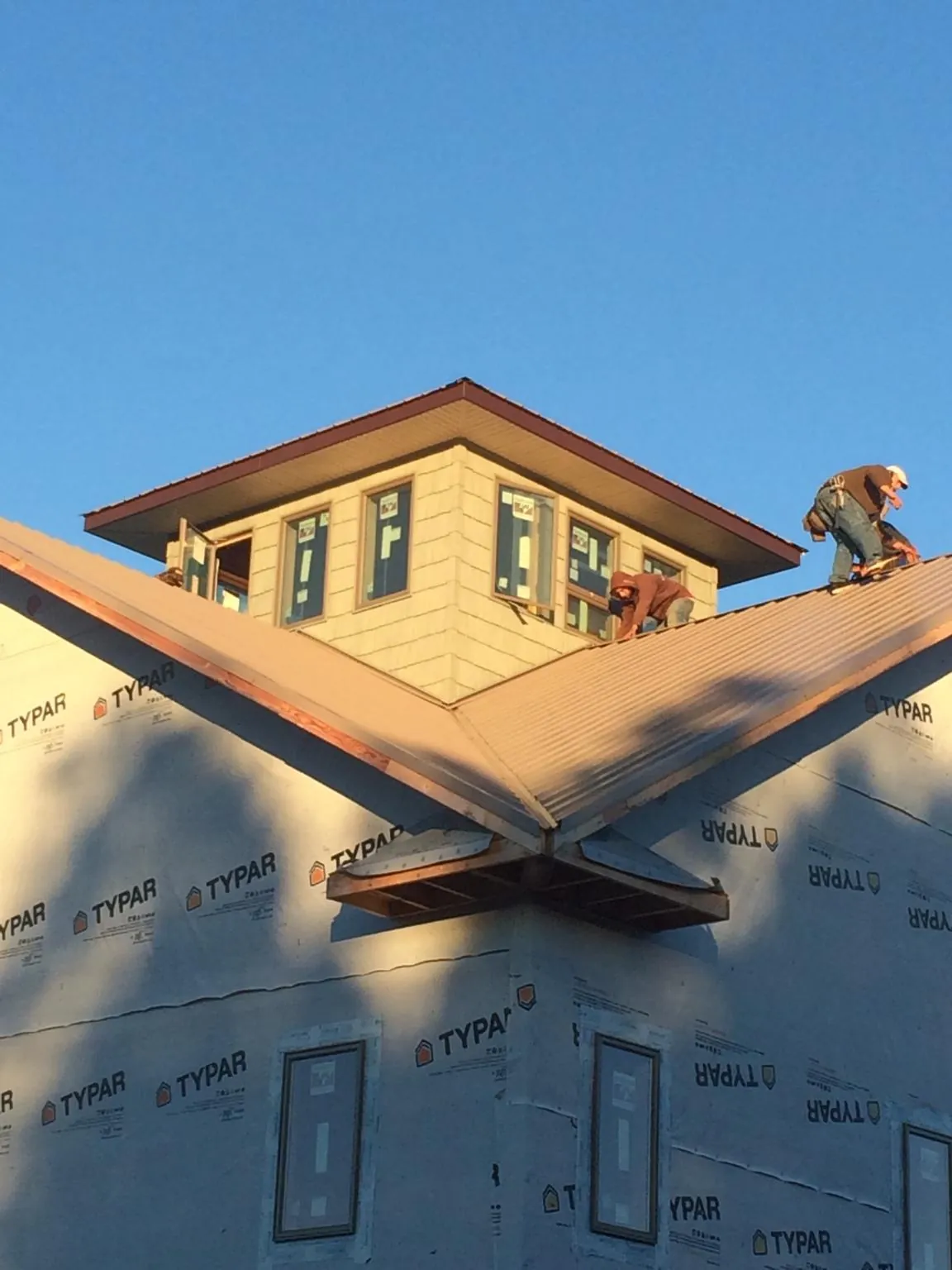 Roofers working around a rooftop cupola on a new metal roof at sunset — Roof Waterproofing in Hospers by Roofing Brothers